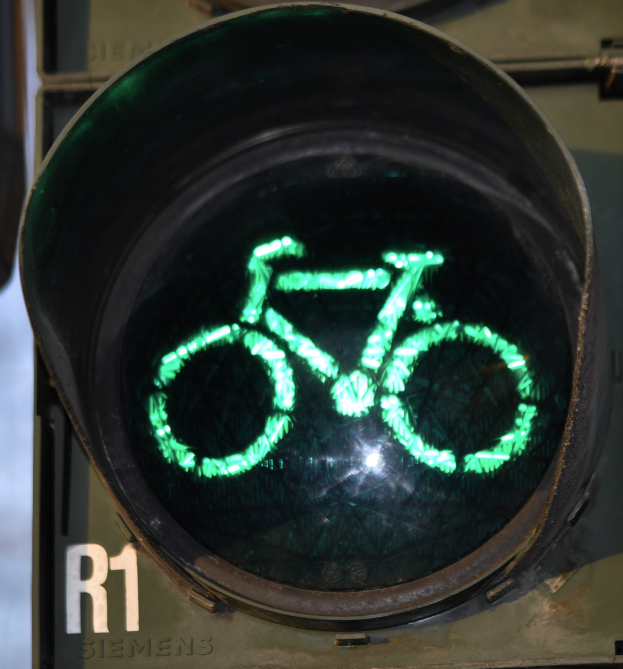 Grünes Ampellicht mit Fahrradsymbol, das an einer Wand leuchtet.