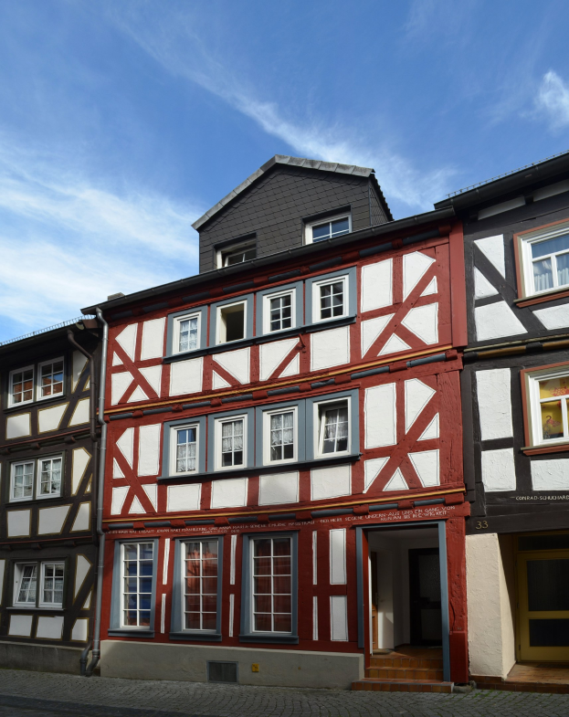 Reihe von Fachwerkhäusern in Heidelbergs Altstadt mit Fenstern, Türen und einem Himmel voller weißer Wolken.