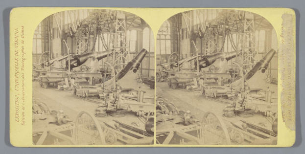 Schwarzes und weißes Foto eines alten Fabrikinneren mit einem gro├čen Geschütz in der Mitte, umgeben von kleineren Geschützen, Metallstangen und anderem Equipment auf dem Boden, mit Text auf der linken Seite.