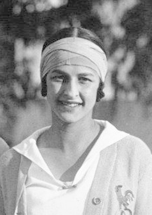 Schwarzes und weißes Foto einer Frau mit Turban, die lächelt, mit unscharfem Hintergrund, als erstes Frauensiegerin eines Tennisturniers bezeichnet.