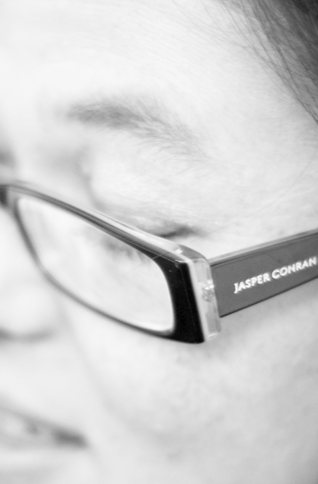 Ein Schwarz-Weiß-Mikrobild einer Person mit Brille, auf der Text steht.