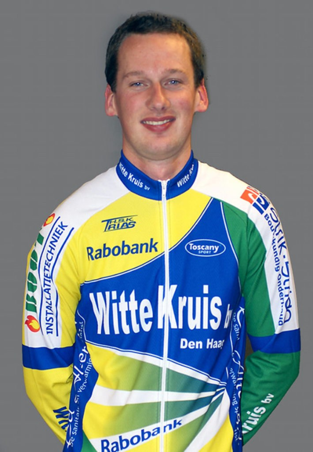 Ein männlicher Sportler posiert für ein Foto, wobei er ein Trikot mit mehreren Sponsorenlogos trägt.