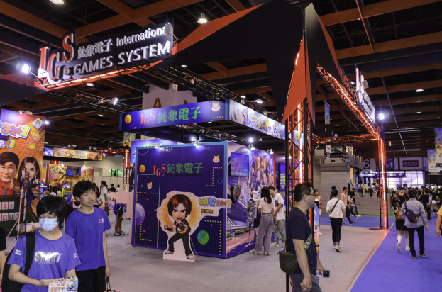 Eine Gruppe von Menschen, die durch einen Convention Hall auf einer Gaming-Messe in China gehen, einige tragen Taschen und halten Gegenstände, mit Display-Boards, Deckenbeleuchtung und Teppichboden.