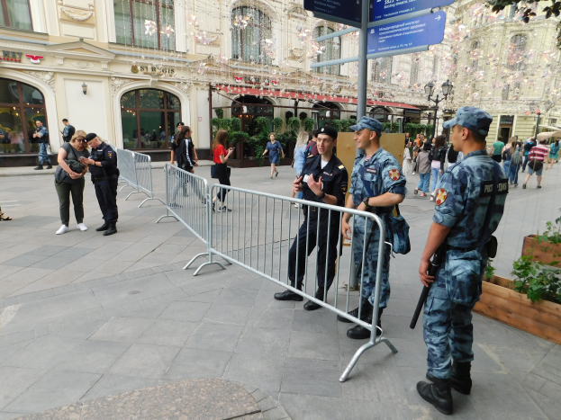 Eine Gruppe von Polizisten steht vor einer Menge, einige halten Waffen, mit Barrikaden und Schildern im Vordergrund und Gebäuden, Laternen, Pflanzen und Bäumen im Hintergrund in Wien, Österreich während eines Anti-Terror-Einsatzes.