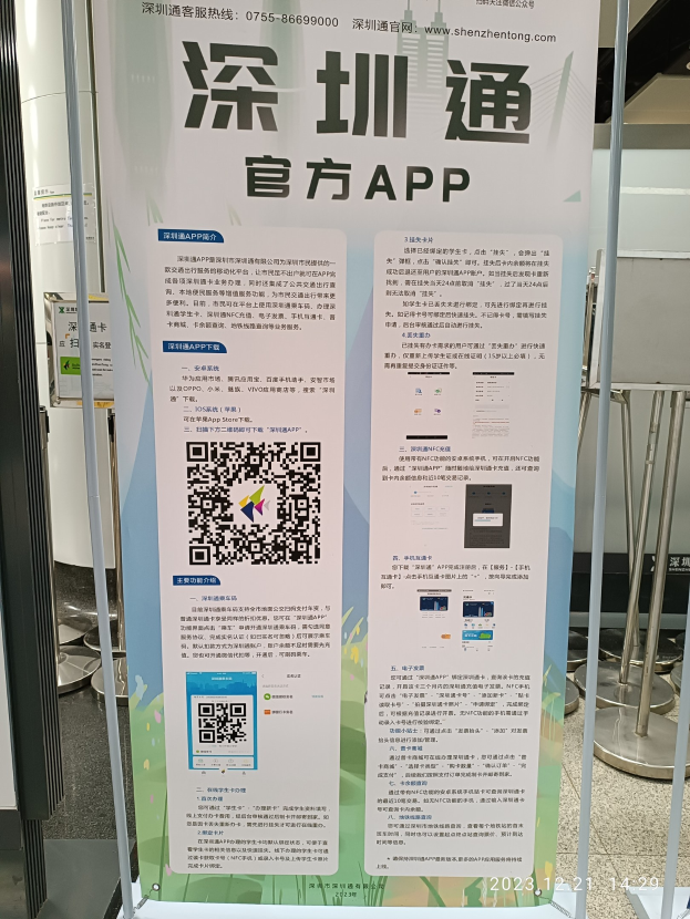 Eine Fahne mit einem QR-Code vor einem Gebäude, wahrscheinlich für den Shenzhen International Airport, umgeben von Ständen und Tafeln.