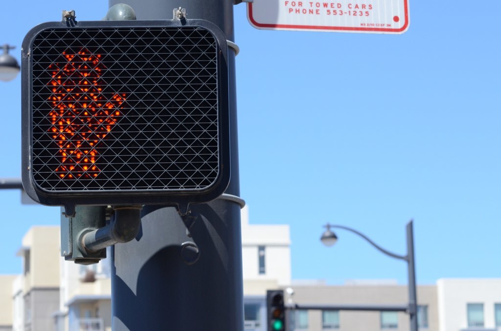 Eine Stadtstraßenszene mit Verkehrspfählen, Ampeln, Straßenlaternen, Gebäuden und Himmel.
