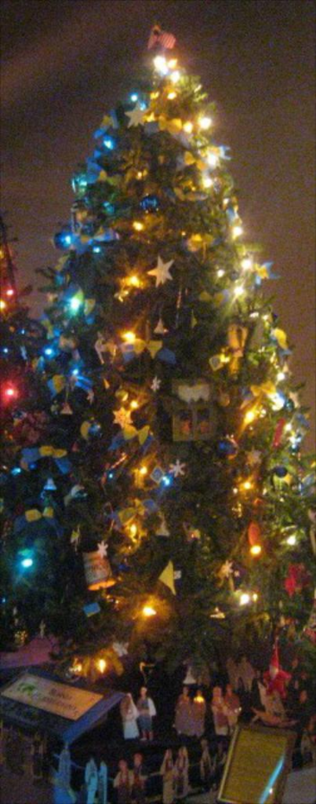 Ein geschmückter Weihnachtsbaum mit Menschenstatuen auf einem darunter platzierten Tisch.