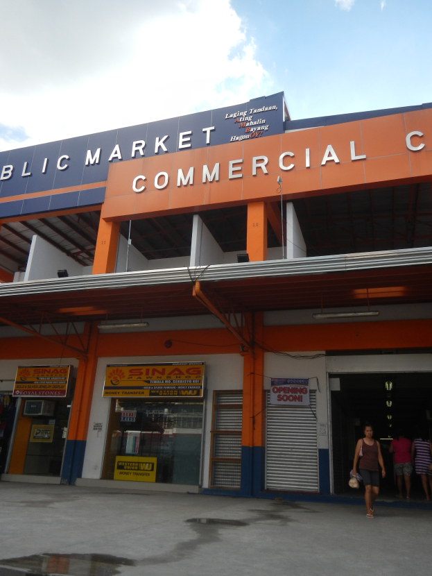 Ein öffentliches Marktzentrum mit Menschen davor, mit Text auf dem Gebäude und einem sichtbaren Himmel oben.