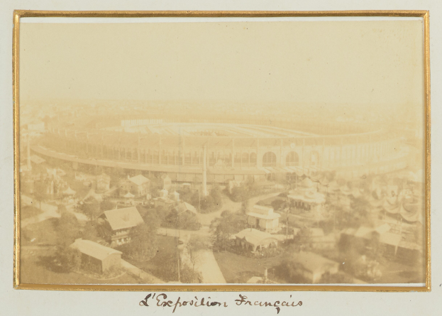 Altes Schwarz-Weiß-Foto eines Stadions in städtischer Umgebung, umgeben von Gebäuden, Bäumen und Strommasten, mit Text unten.
