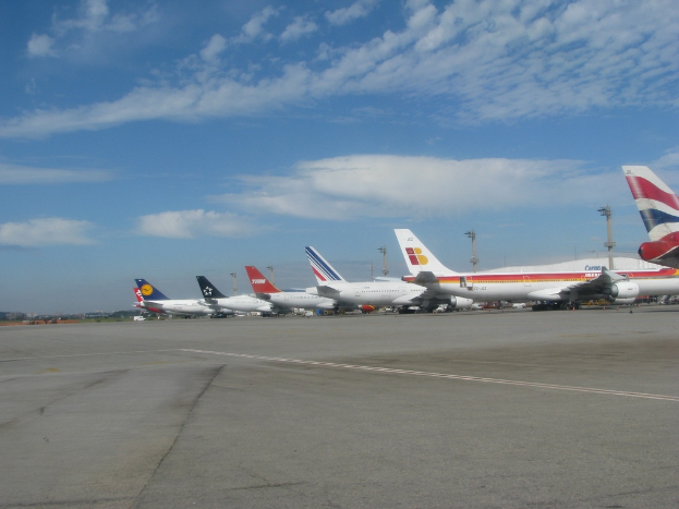 Eine Start- und Landebahn mit wenigen Flugzeugen, Masten, Kabeln und einer bewölkten Himmel