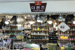 Ein unordentlicher Laden in Seoul, der verschiedene Gegenstände wie Körbe, Lampen, Flaschen und Spielzeuge auf Regalen ausstellt, mit einem Schild oben, das ihn als einen der besten koreanischen Läden ausweist.