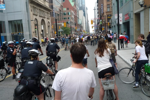 Gebäude und einige Menschen auf Fahrrädern auf einer Straße.