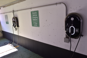 Elektrofahrzeug-Ladestationen an einer Wand in einer Tiefgarage mit Informationsschildern darunter.