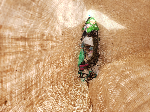 Nahaufnahme eines Stücks Abfallpapier auf einem Tisch mit einem Jutestoff im Hintergrund.