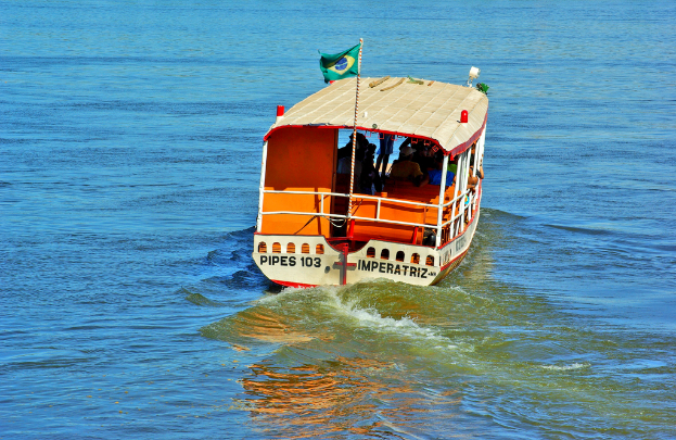 Ein Boot mit Menschen und einer Flagge mit Text fährt auf dem Wasser.