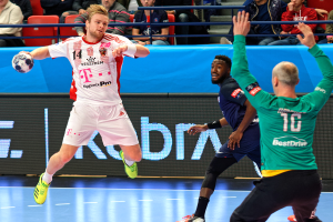 Eine Gruppe von Männern, die Handball auf einem Platz mit einem Ball in der Mitte spielen, während Zuschauer von Stühlen und Geländern im Hintergrund zusehen, mit einer Tafel, auf der "Futsal-Weltmeisterschaft 2019 - Bayern München vs. Paris Saint-Germain" steht.