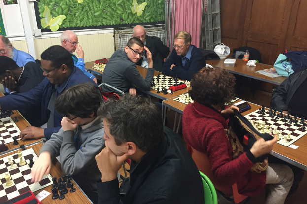 Eine Gruppe von Menschen, die um einen Tisch herum sitzen und Schach spielen.