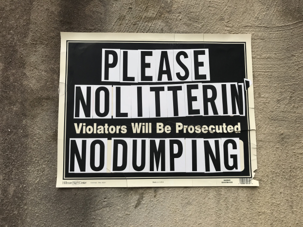 Schwarzes und weißes Schild an einem Gebäude mit der Aufschrift "Bitte Kein Müll Verunreiniger Werden Verfolgt Keine Ablagerung".
