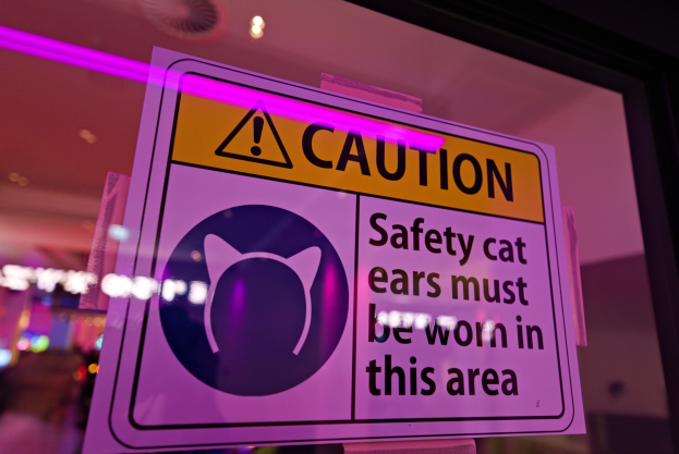 Vorsichtsschild in einem Ladenschaufenster, das den Gebrauch von Sicherheitskatzenohren im Bereich erfordert.