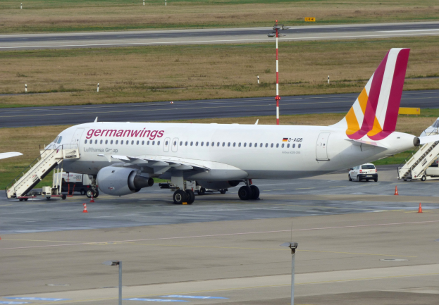 Germanwings Airbus A320-200 am Frankfurter Flughafen mit Bodenfahrzeugen, Verkehrskegeln, Versorgungsmasten und grüner Fläche im Hintergrund.