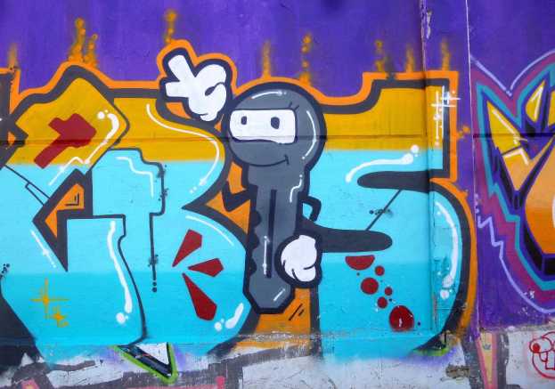 Eine Wand voller farbenfroher Graffiti mit einem hellen Cartoon-Charakter in verschiedenen Formen und Größen