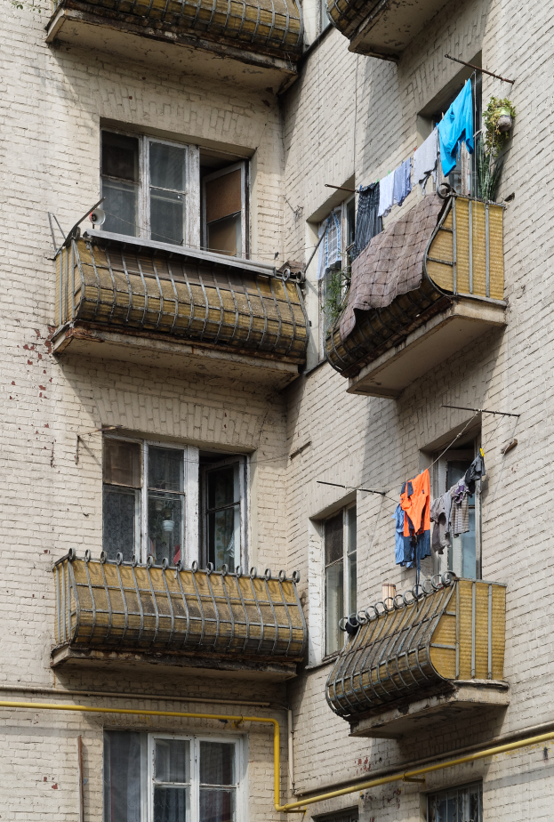 Ein Wohnhaus mit Fenstern, Balkonen und zum Trocknen aufgehängter Wäsche, mit Leitungen an der Seite.