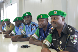 Gruppe von Polizeibeamten sitzt an einem Tisch während einer Schulung, mit Mobiltelefonen und anderen Gegenständen auf dem Tisch, in einem Raum mit Fenstern und Deckenbeleuchtung.