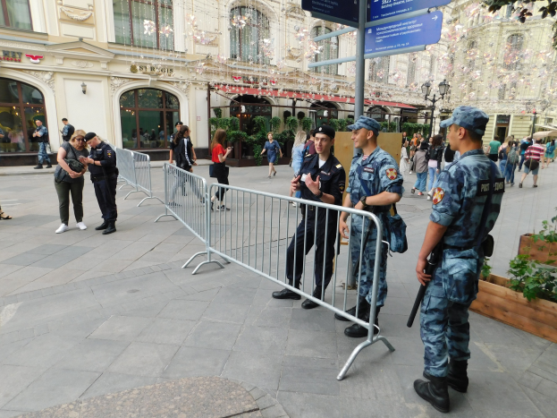 Polizeibeamte in Uniform stehen hinter Absperrungen und blicken auf eine Menge, von der einige Mützen tragen und Waffen halten, während sie eine Anti-Terror-Operation in Wien, Österreich, durchführen.