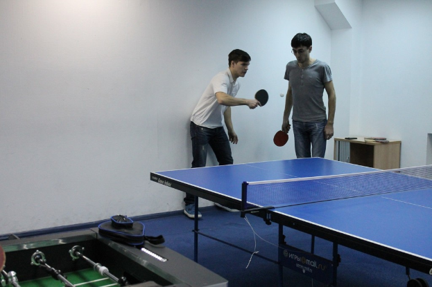 Zwei Personen spielen Tischtennis, eine auf jeder Seite des Tisches.
