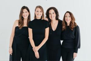 Vier Frauen in schwarzen Kleidern, die für ein professionelles Headshot posen, mit Wasserzeichen oben und unten.