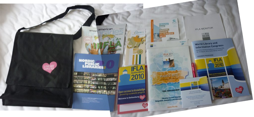 Eine Tasche mit 'Bibliothek-Liebhaber' drauf und einige Bücher auf einem Bett.