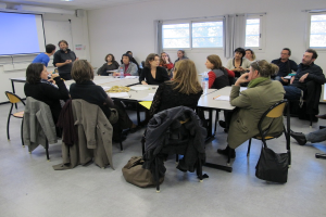 Eine Gruppe von Menschen, die sich unterhält und diskutiert, mit zwei Personen im Hintergrund, die miteinander sprechen.