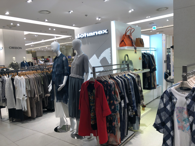 Ein Bekleidungsgeschäftsinneres mit Schaufensterpuppen, Kleiderstangen, Handtaschen, Schildern, Deckenleuchten und einer Säule, das sich im Mall of Asia als Teil der Johanex-Marke befindet.