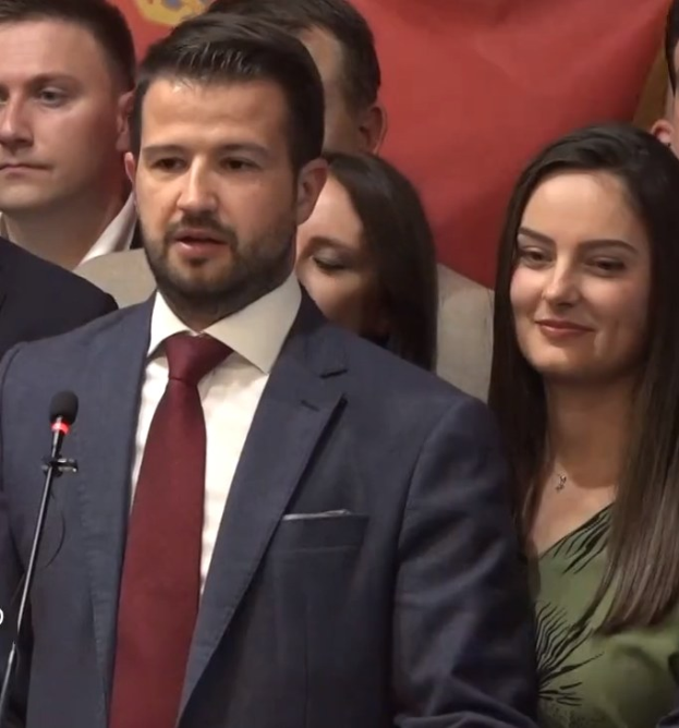 Ein Mann im Anzug spricht an einem Rednerpult mit einem Mikrofon zu einer Menge hinter einem Banner, wahrscheinlich über ein Regierungverbot von Social Media.