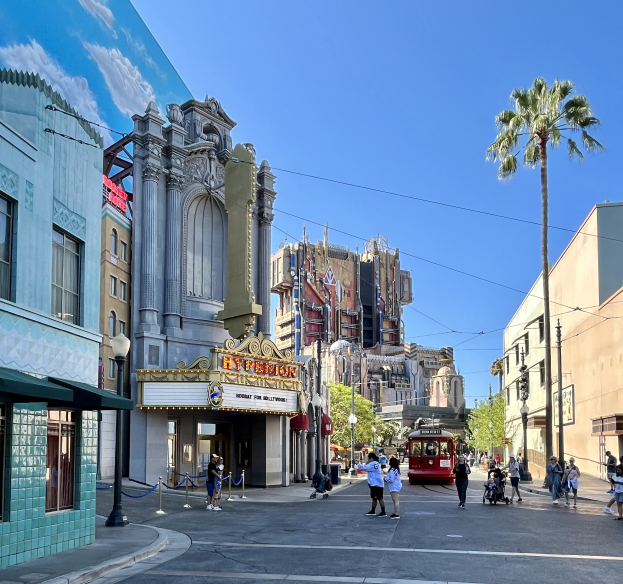Lebendige StraßenSzene im Universal Studios Hollywood mit Passanten, einem Fahrzeug, Bäumen, Straßenmöbeln und einem Gebäude im Hintergrund.