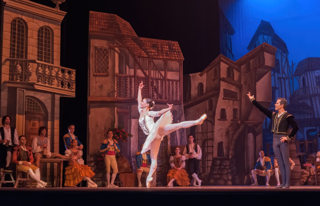 Zwei Tänzer performen auf der Bühne der Royal Opera House in London, mit einem sitzenden und stehenden Publikum im Hintergrund.