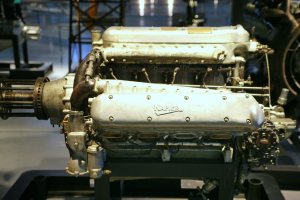 Eine Maschine mit Text darauf ist zentral positioniert, mit einem schwarzen Ständer im Hintergrund und einer weiteren Maschine rechts daneben.