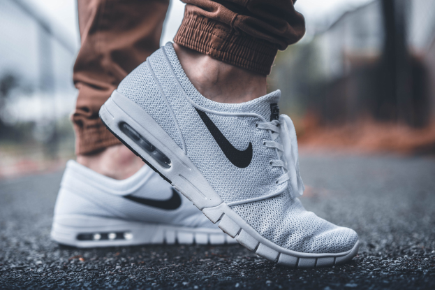Eine Person in schwarzen und weißen Nike SB Stefan Janoski Max-Schuhen in Wolf Grau vor einem unscharfen Hintergrund.