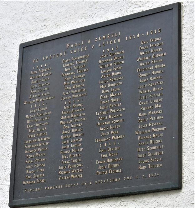 Eine dunkle Plakette an einer Gebäudewand mit einem dekorativen Rahmen, auf der der Text "Plakette für die Opfer des Holocaust" in fetter Schrift steht.