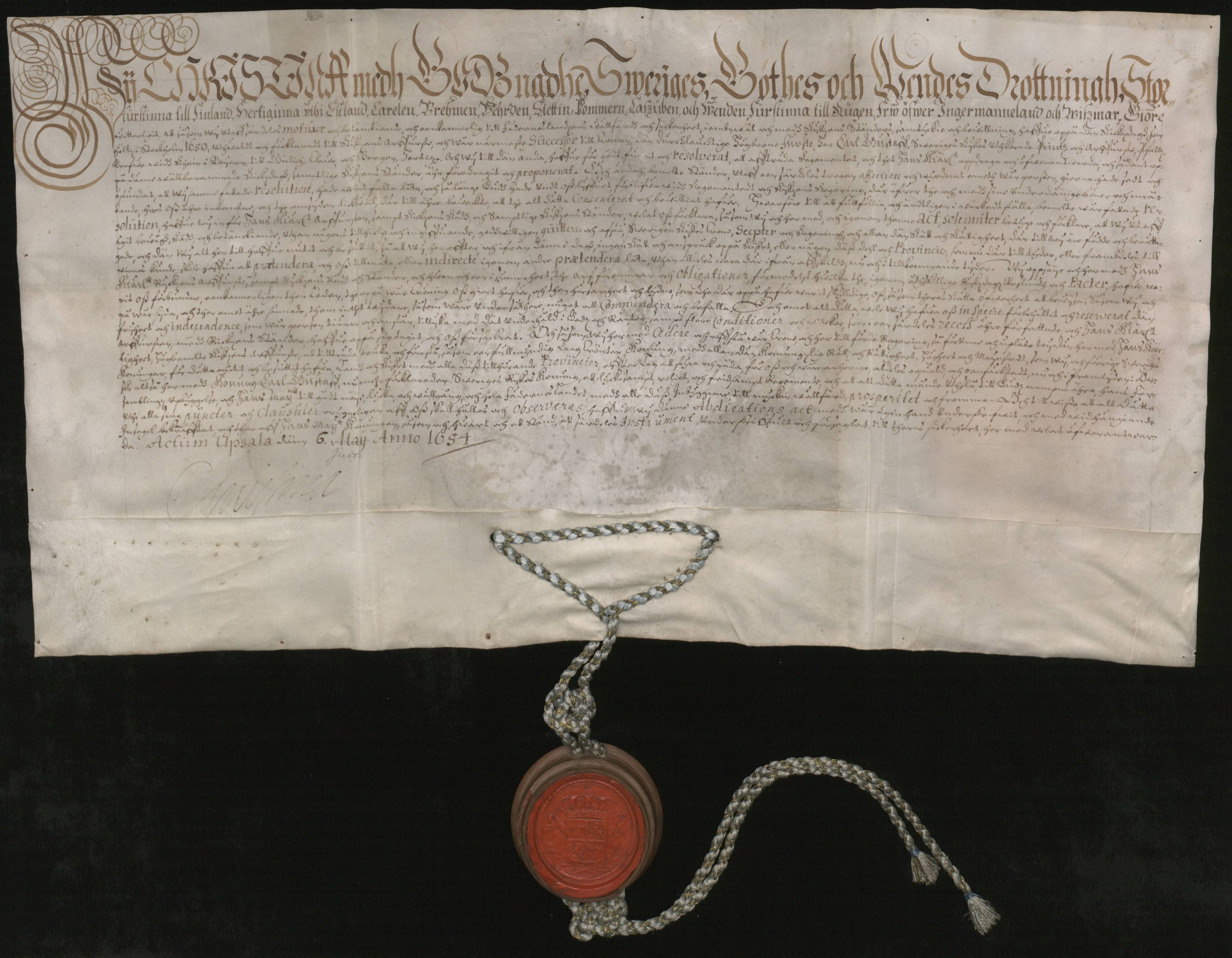 Altes Dokument mit rotem Wachssiegel an einer Kette befestigt, sieht aus wie ein Vertrag mit Text.