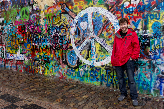 Eine Person steht vor einer Wand mit Graffiti, mit einem Gehweg unten.