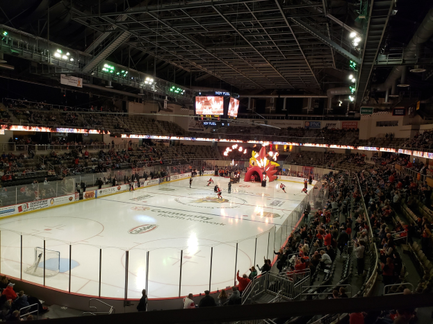 Eishockeyspiel in einer großen Arena mit Sitzplätzen und Stehplätzen, umgeben von einer Bande, Bannern, Überdachung, Metallstangen, Lampen und Bildschirmen, identifiziert als Nationwide Arena.