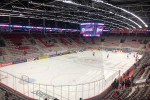 Eishockeyspiel zwischen den St. Louis Blues und den Detroit Red Wings in einer großen Arena mit Zuschauern, Eisbahn von einem Zaun umgeben und ein Display mit den Teamnamen.