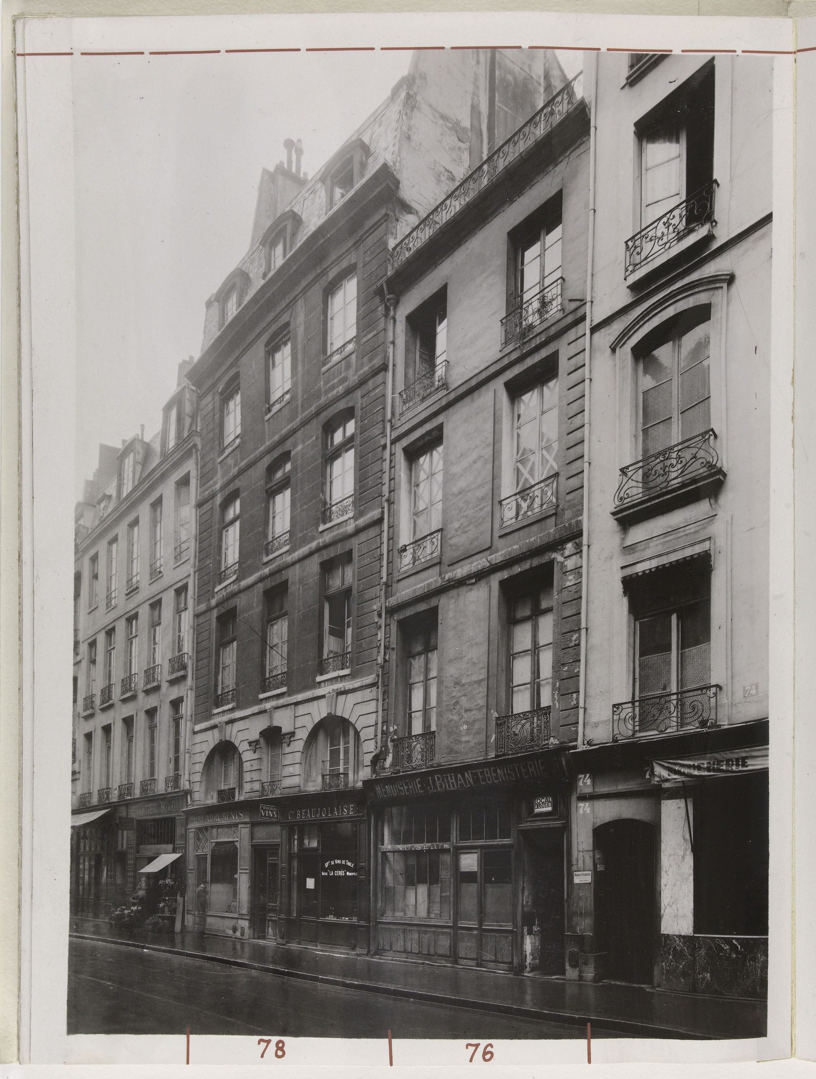 Schwarz-weiß-Foto einer Stra├če mit Geb├Ąuden mit Fenstern, Gel├Ąndern und Namensschildern sowie einer Stra├če unten.