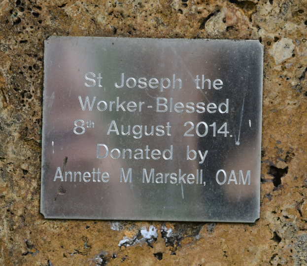 Eine Steinwand mit einer Metalltafel, auf der "St. Josef der Arbeiter-Gesegnet 8. August 2014" steht.