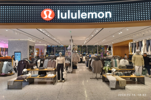 Das Innere eines lululemon-Ladens in Singapur mit Schaufensterpuppen in aktuellen Modellen, Kleidung an Bügeln und Tischen mit verschiedenen Artikeln, alles unter Deckenbeleuchtung mit einem Namensschild und einem Wasserzeichen auf dem Bild.