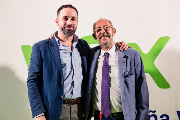 Zwei Männer in Anzügen lächeln nebeneinander vor einer Wand, wobei der Mann rechts eine Brille trägt; ein Schild im Hintergrund trägt die Aufschrift "Vodafone und Vodacom kündigen Partnerschaft an".